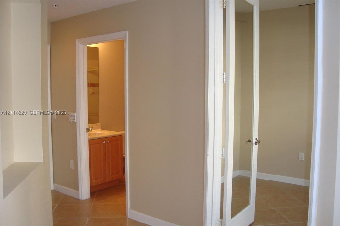 Tile flooring, wood-finish cabinetry with a countertop basin, and mirrored door panels