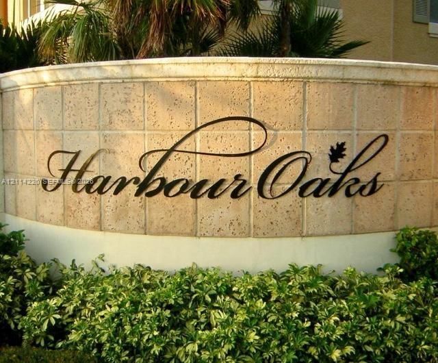 Curved masonry monument sign featuring square-tile textured cladding, dimensional metal lettering, and established perimeter shrubbery