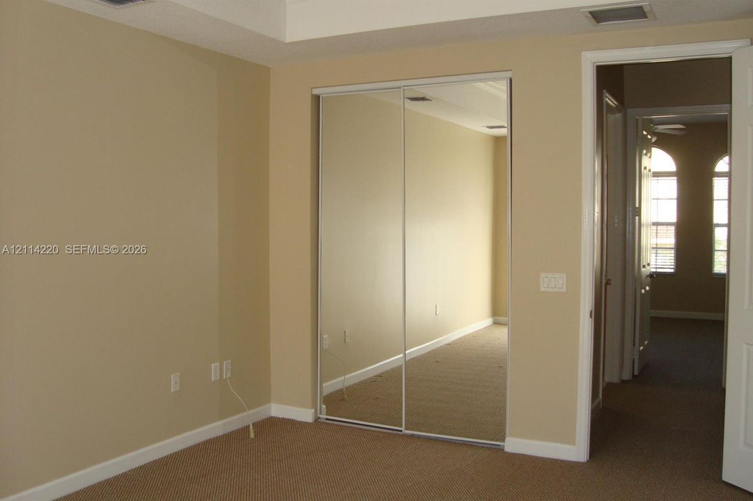 Room interior featuring a tray ceiling, wall-to-wall carpeting, and sliding mirrored closet doors