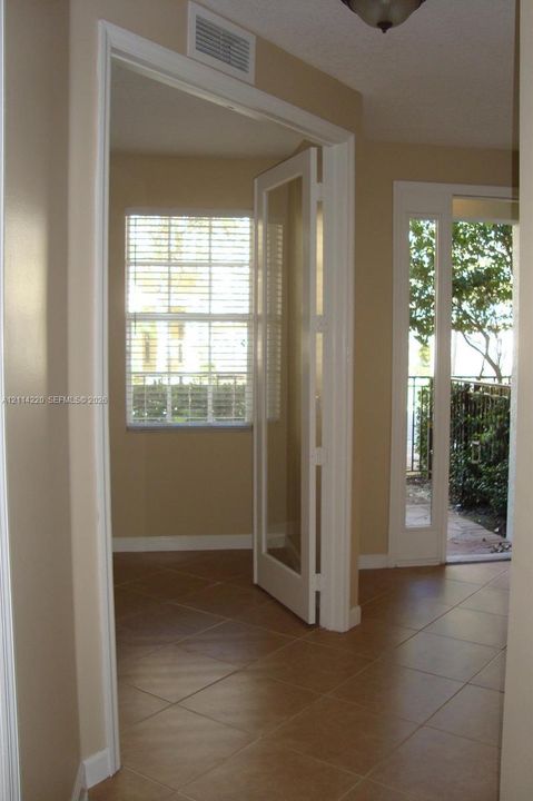 Ceramic tile flooring, white-trimmed glass paneled door, and glass exterior door opening to a patio