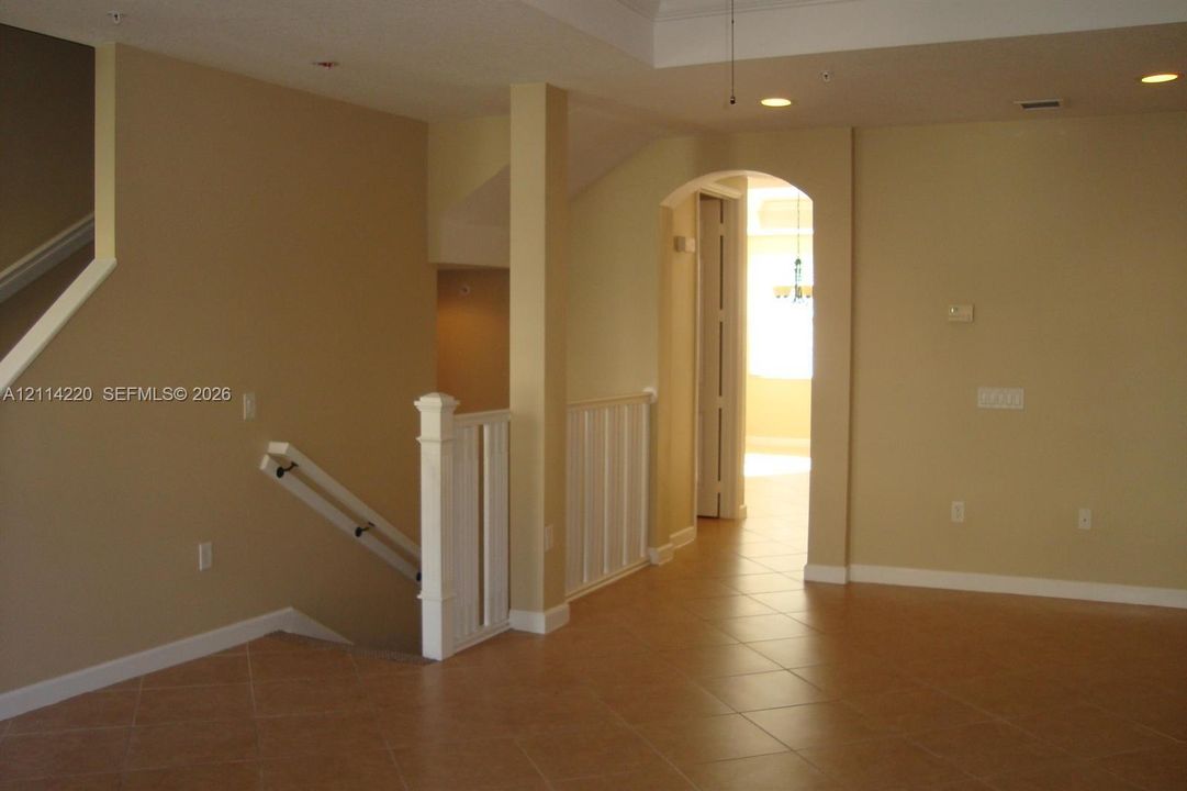 Interior featuring tile flooring, recessed ceiling lighting, a tray ceiling, and a prominent arched entryway