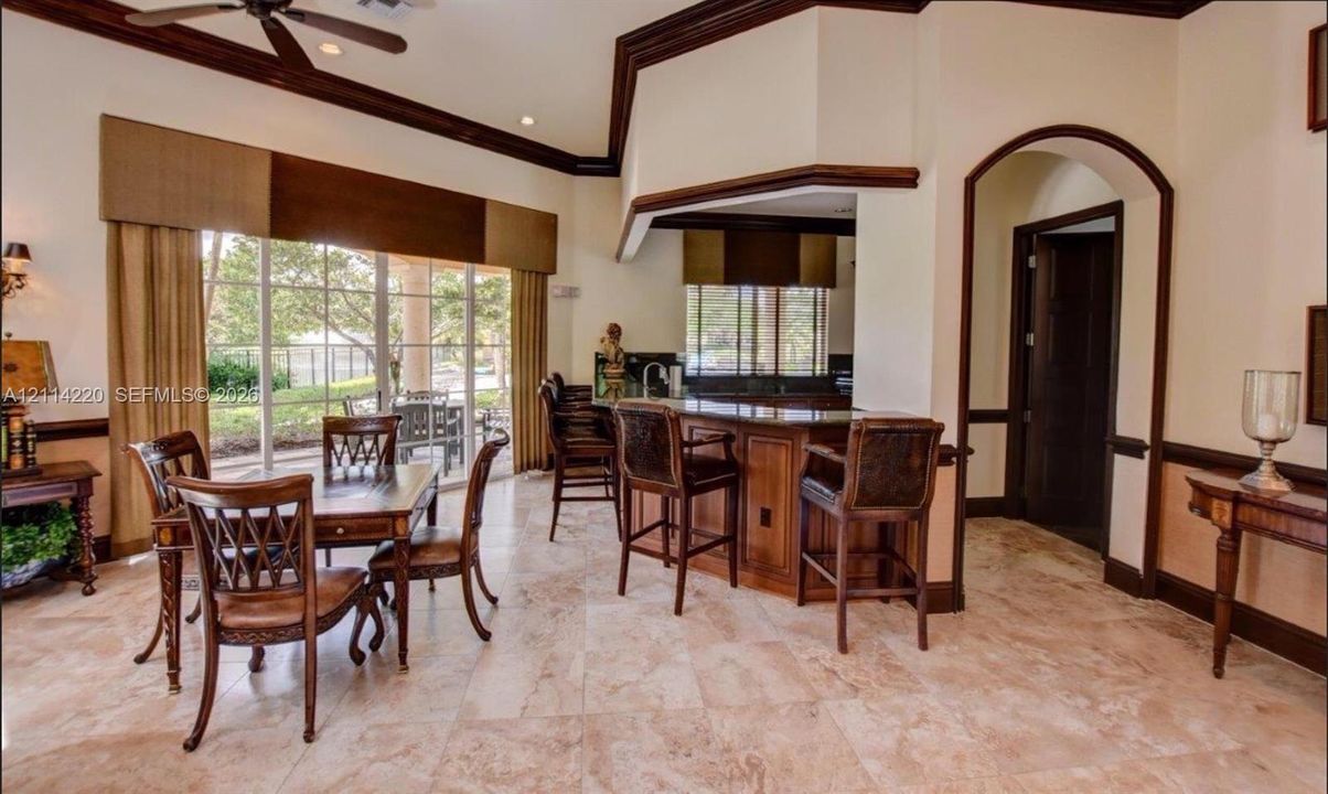 Vaulted ceilings with crown molding, natural stone tile flooring, built-in wet bar with stone countertop, and glass sliding doors