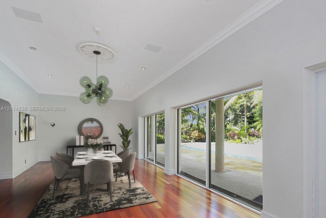 Spacious dining area featuring wood-finish flooring, a decorative ceiling medallion, recessed lighting, and expansive floor-to-ceiling sliding glass doors opening to a paved patio area
