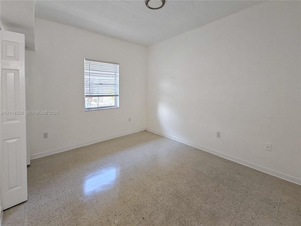 Neutral-toned interior featuring smooth-finish walls, polished hard-surface flooring, a single-panel closet door, and a horizontal-slat window blind