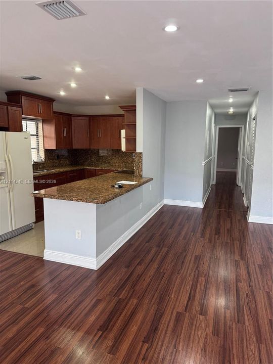 Kitchen featuring wood-finish cabinetry, stone-surface countertops, an integrated breakfast bar, and recessed lighting throughout