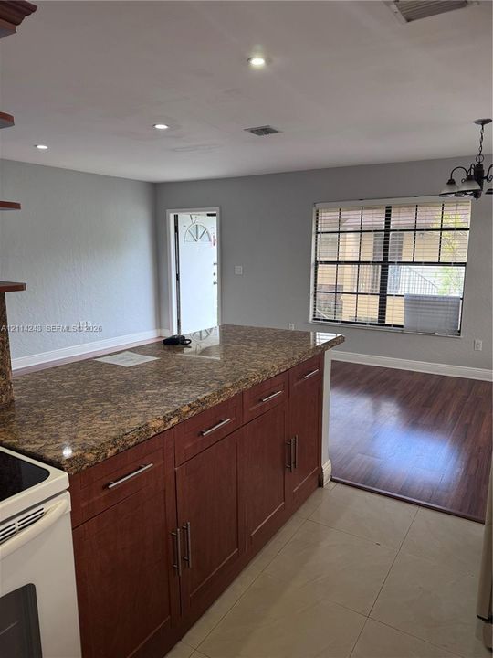 Kitchen featuring a stone-surface countertop, dark-finish cabinetry with silver hardware, recessed ceiling lighting, and large-format tile flooring