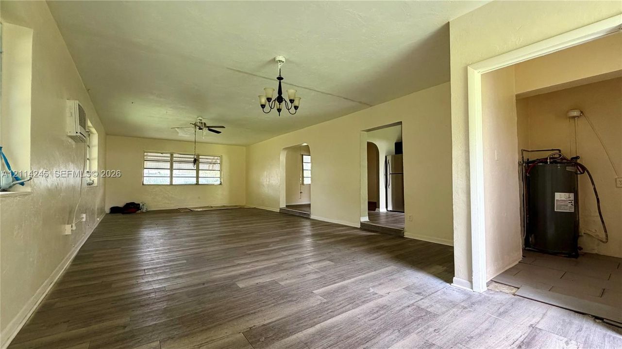 Interior space featuring wood-finish flooring, multi-pane windows, arched entryways, and a multi-arm chandelier