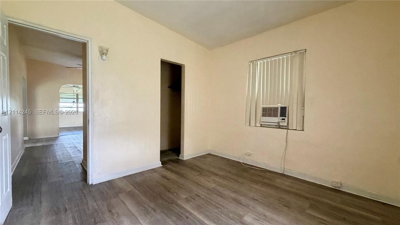 Interior space featuring wood-finish flooring, neutral wall tones, a built-in closet, and a window with vertical blinds