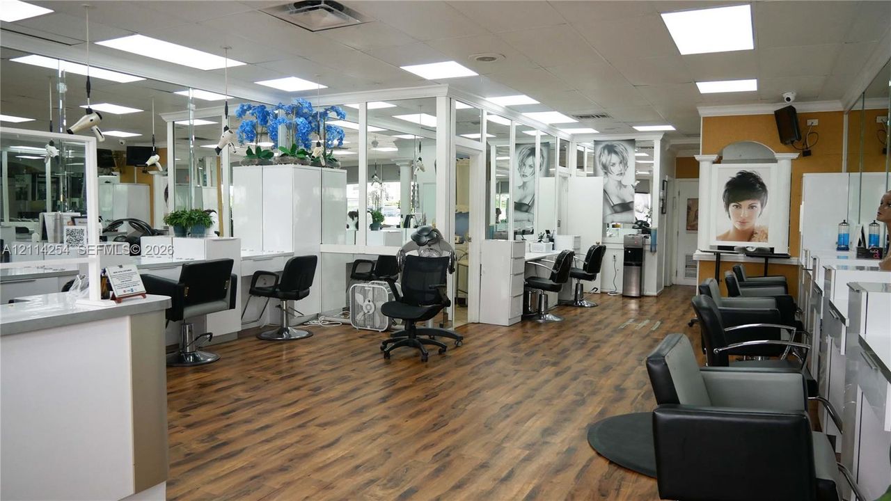 Wood-finish flooring, extensive wall mirrors, drop-ceiling grid with recessed lighting, and white laminate cabinetry