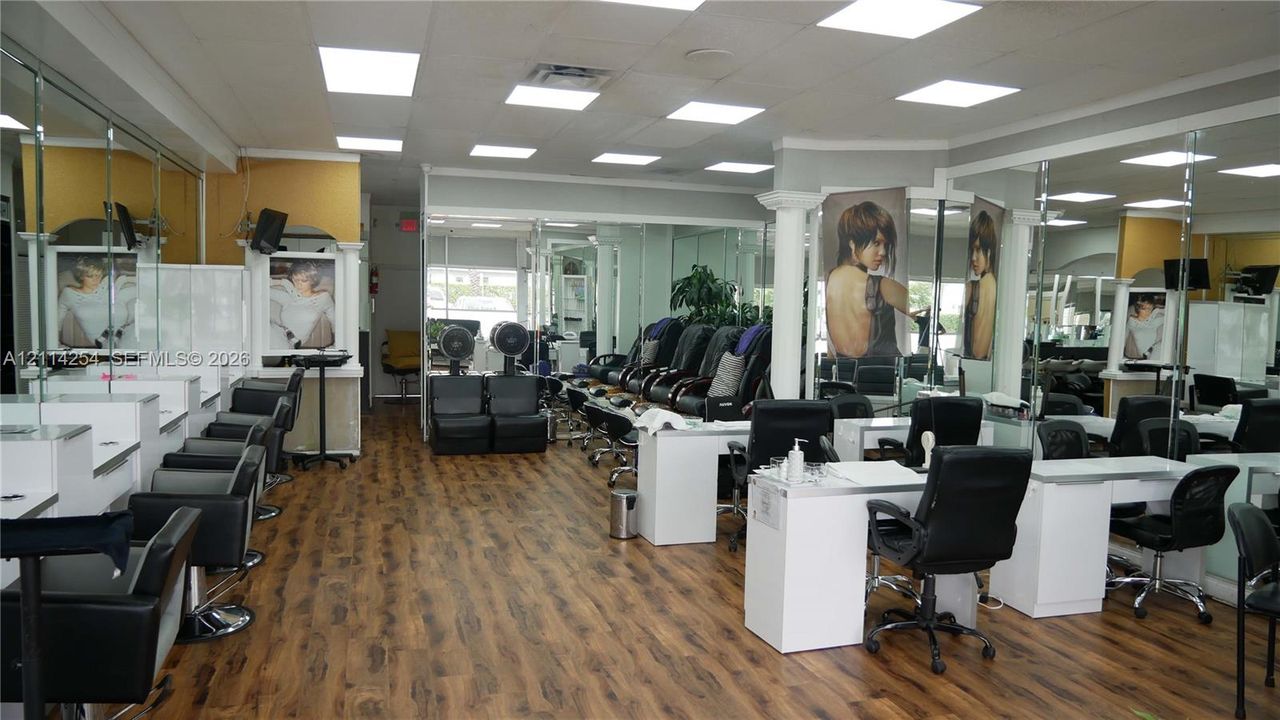 Commercial interior featuring wood-finish flooring, recessed LED panel lighting, full-wall mirrors, and built-in service stations with stone-finish countertops
