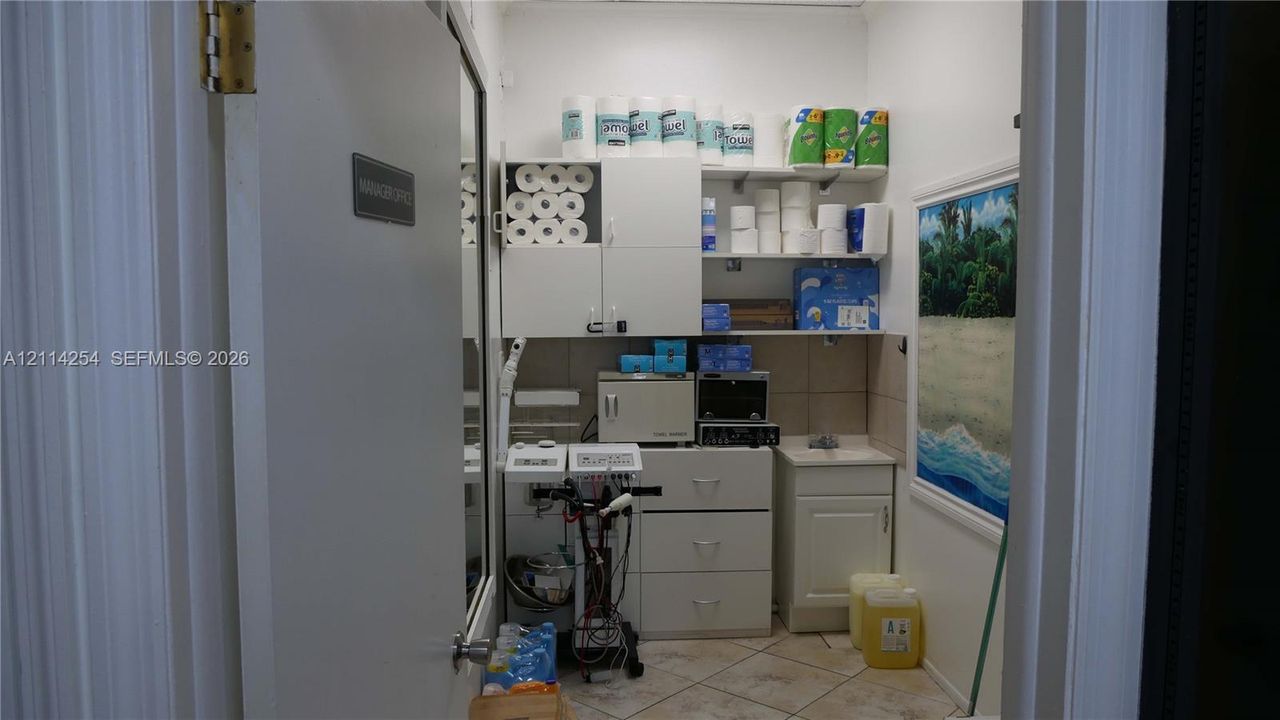 Storage room featuring white cabinetry, a single-basin sink with countertop, tile flooring, and open shelving
