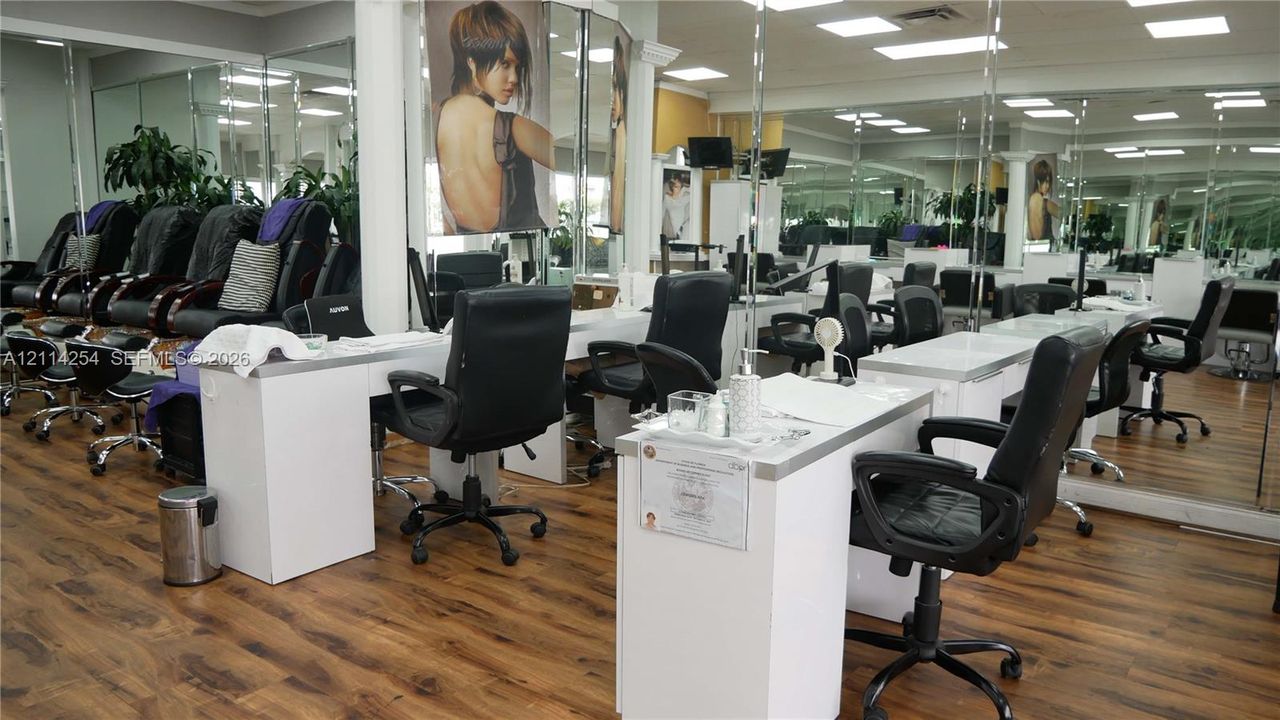 Commercial space featuring wood-finish flooring, extensive wall-to-wall mirrors, recessed lighting, and built-in white laminate workstations