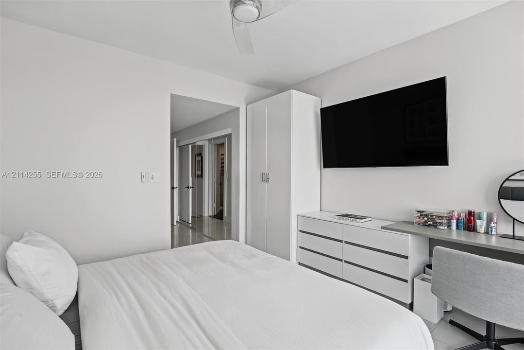 Room interior featuring high-gloss white built-in cabinetry, smooth-finish ceilings with a central fan, and neutral flooring