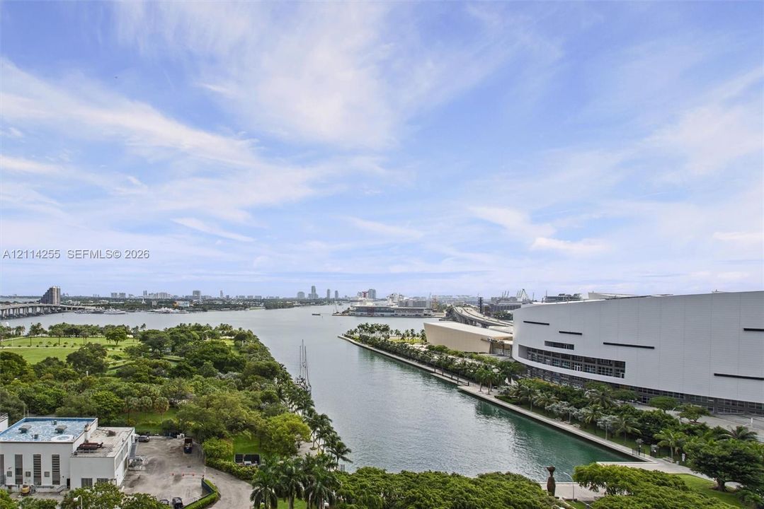 Elevated perspective featuring coastal waters, urban skyline, public park space, and bridge infrastructure