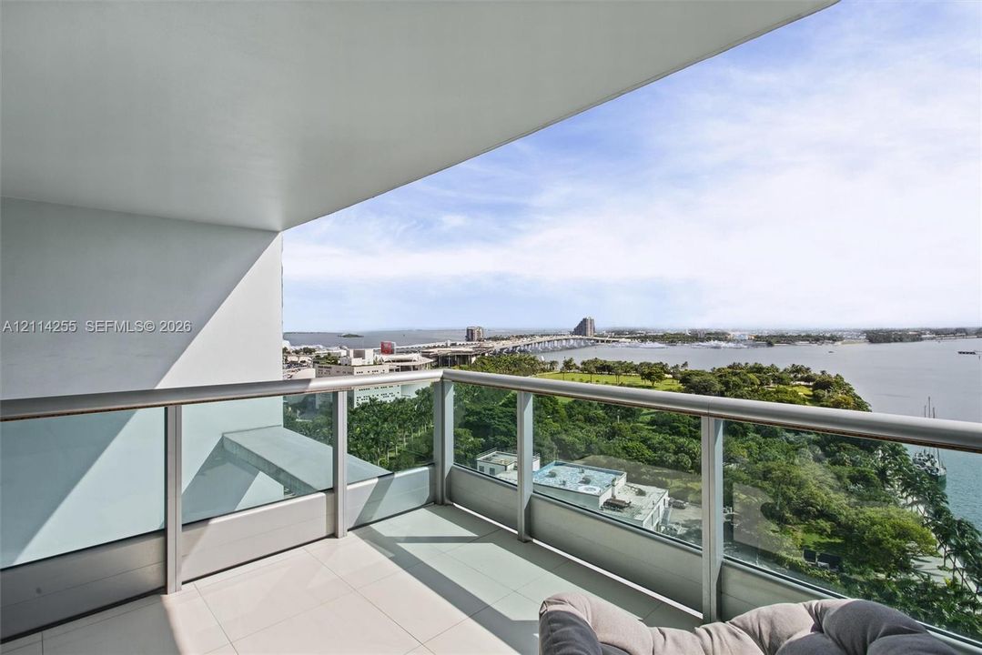 Covered balcony featuring tile flooring and a glass-paneled metal railing