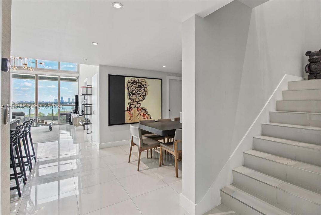 Polished tile flooring, floor-to-ceiling windows with water scenery, recessed lighting, and a staircase with tile treads
