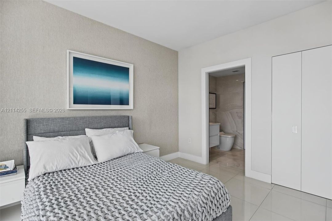 Neutral-toned textured accent wall featuring smooth-finish flooring, minimalist double-door closet cabinetry, and a clean-lined interior doorway