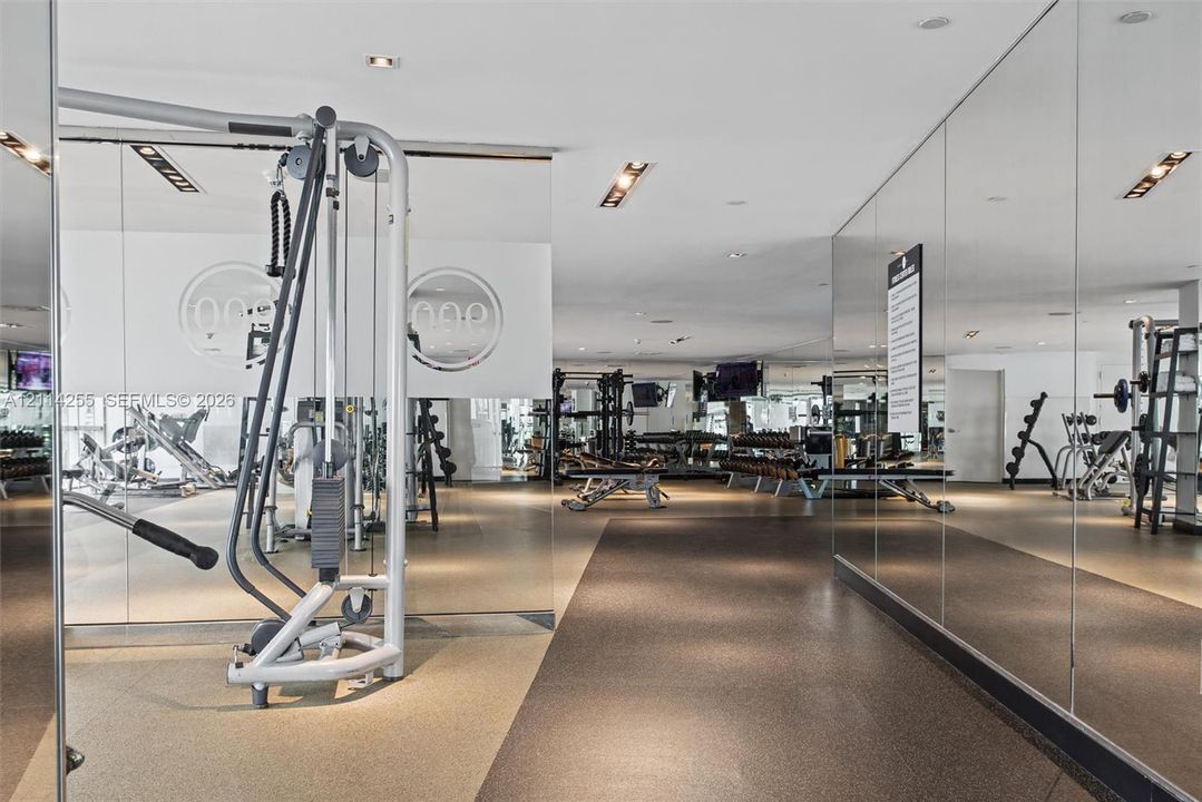 Expansive fitness facility featuring wall-to-wall mirrors, recessed lighting, and durable rubber flooring