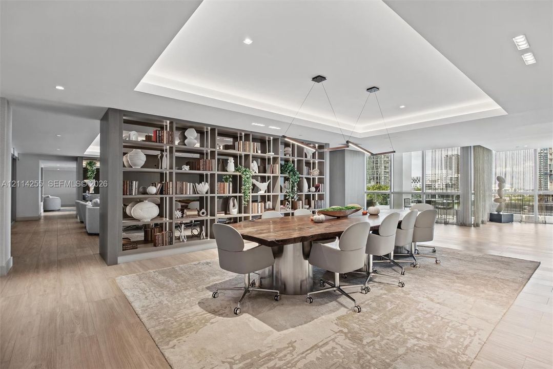 Open-concept space featuring wood-finish flooring, a tray ceiling with recessed lighting, floor-to-ceiling windows, and custom floor-to-ceiling built-in shelving