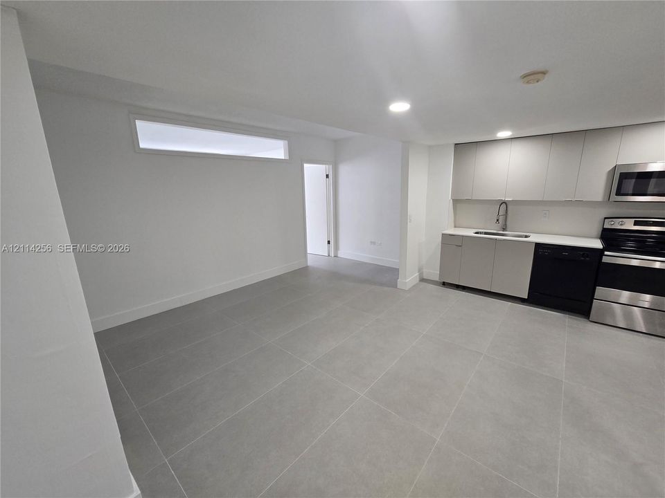 Kitchen featuring flat-panel cabinetry, quartz countertops, stainless steel appliances, large-format tile flooring, and recessed lighting