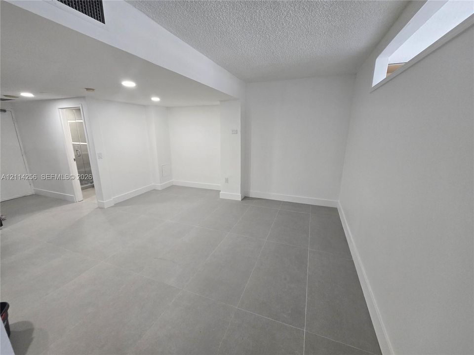Interior space featuring large-format grey tile flooring, recessed ceiling lighting, and horizontal transom windows
