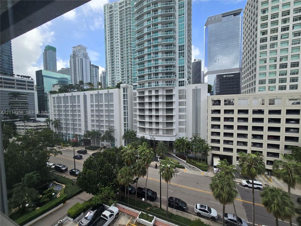 High-rise urban setting featuring tiered glass architecture, integrated parking structures, and mature palm landscaping