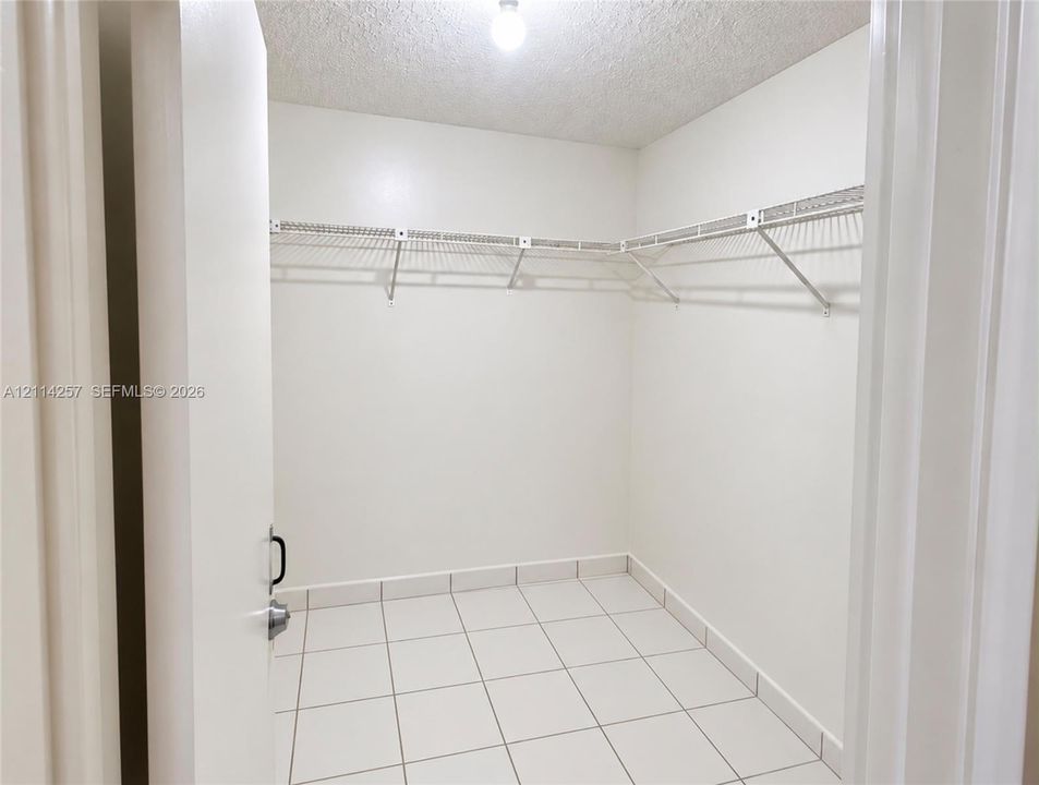 Storage area featuring tile flooring, white walls, and built-in white wire shelving