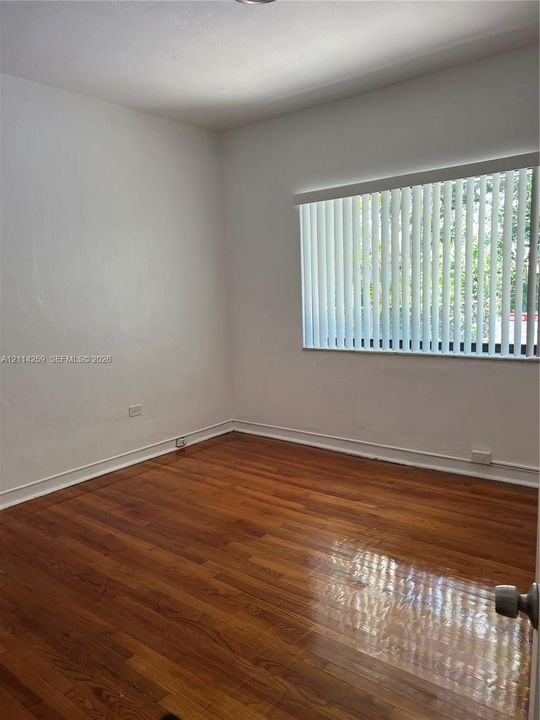 Room featuring wood-finish flooring and a horizontal window with vertical blinds