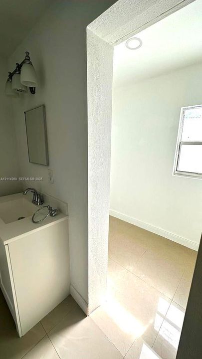 Vanity featuring an integrated sink with a chrome faucet, tri-light fixture, tile flooring, and recessed ceiling lighting