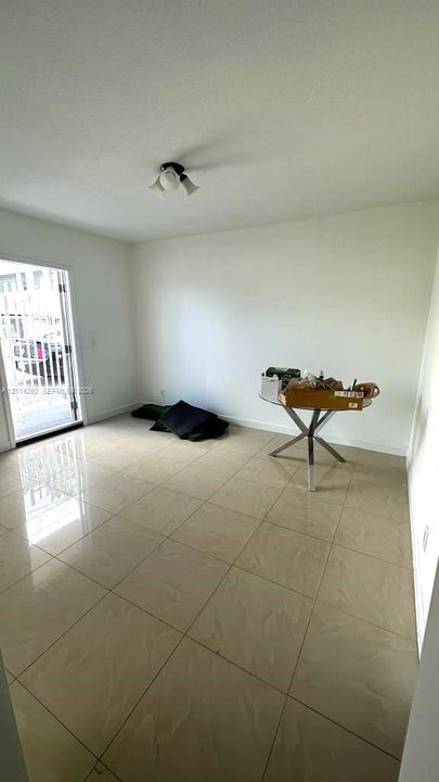 Large-format tile flooring, multi-pane glass door with metal security gate, and ceiling-mounted light fixture