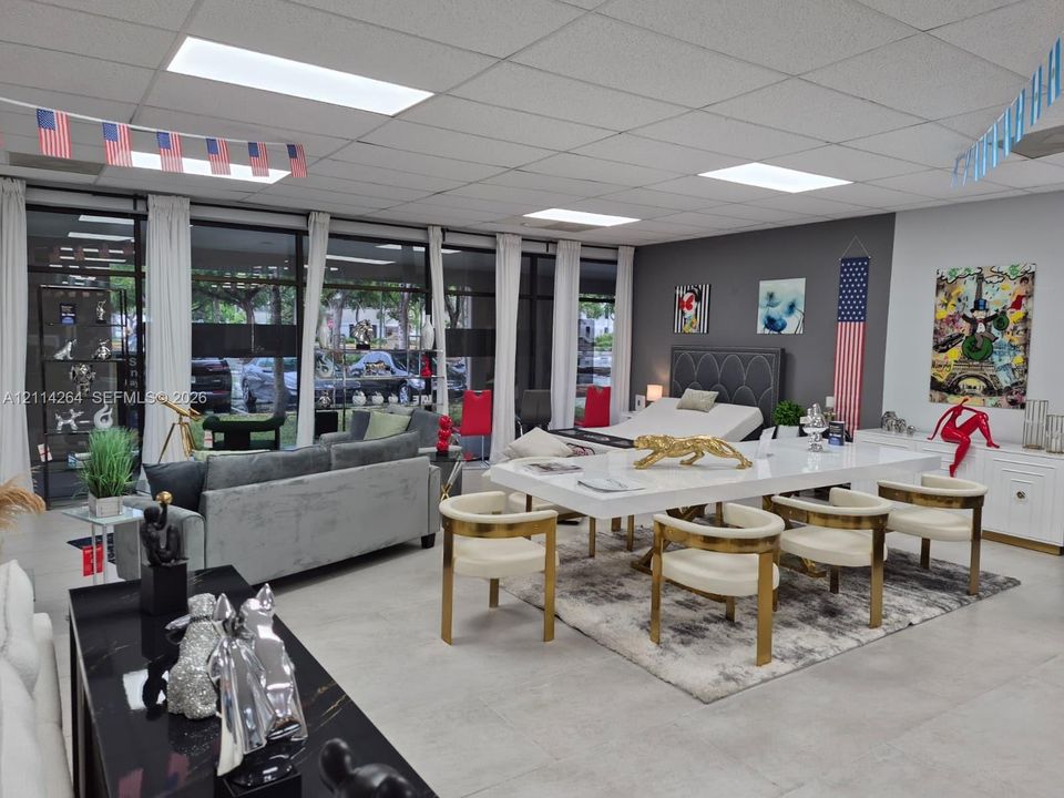 Open-concept interior space featuring floor-to-ceiling glass wall panels, smooth concrete-finish flooring, and recessed drop-ceiling lighting