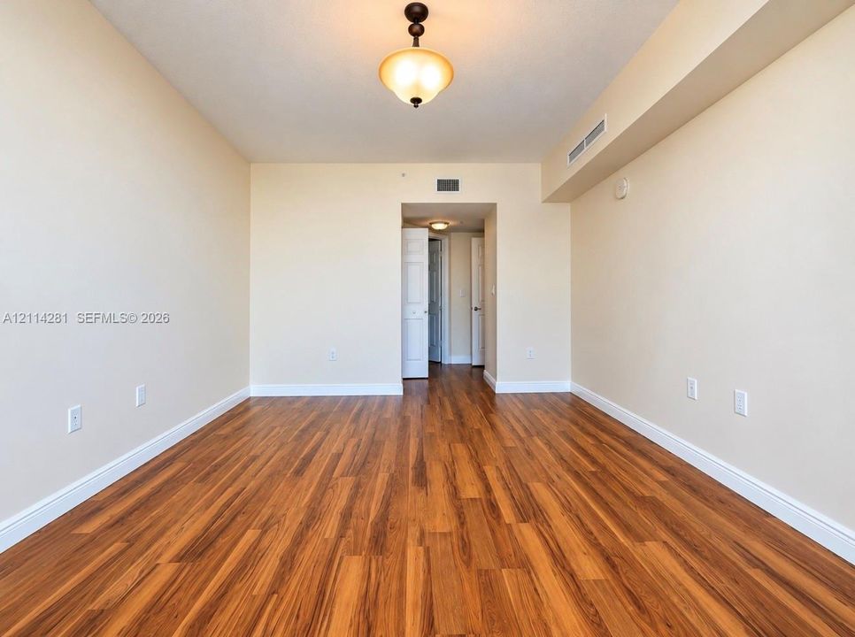 Interior space featuring wood-finish flooring, neutral wall tones, a ceiling-mounted semi-flush light fixture, and interior doors