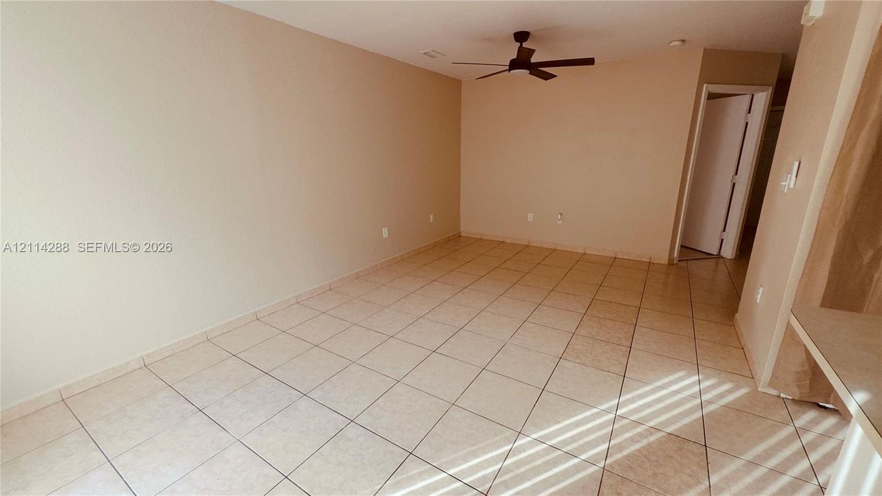 Neutral-toned interior space featuring square ceramic tile flooring and a ceiling-mounted fan with integrated lighting