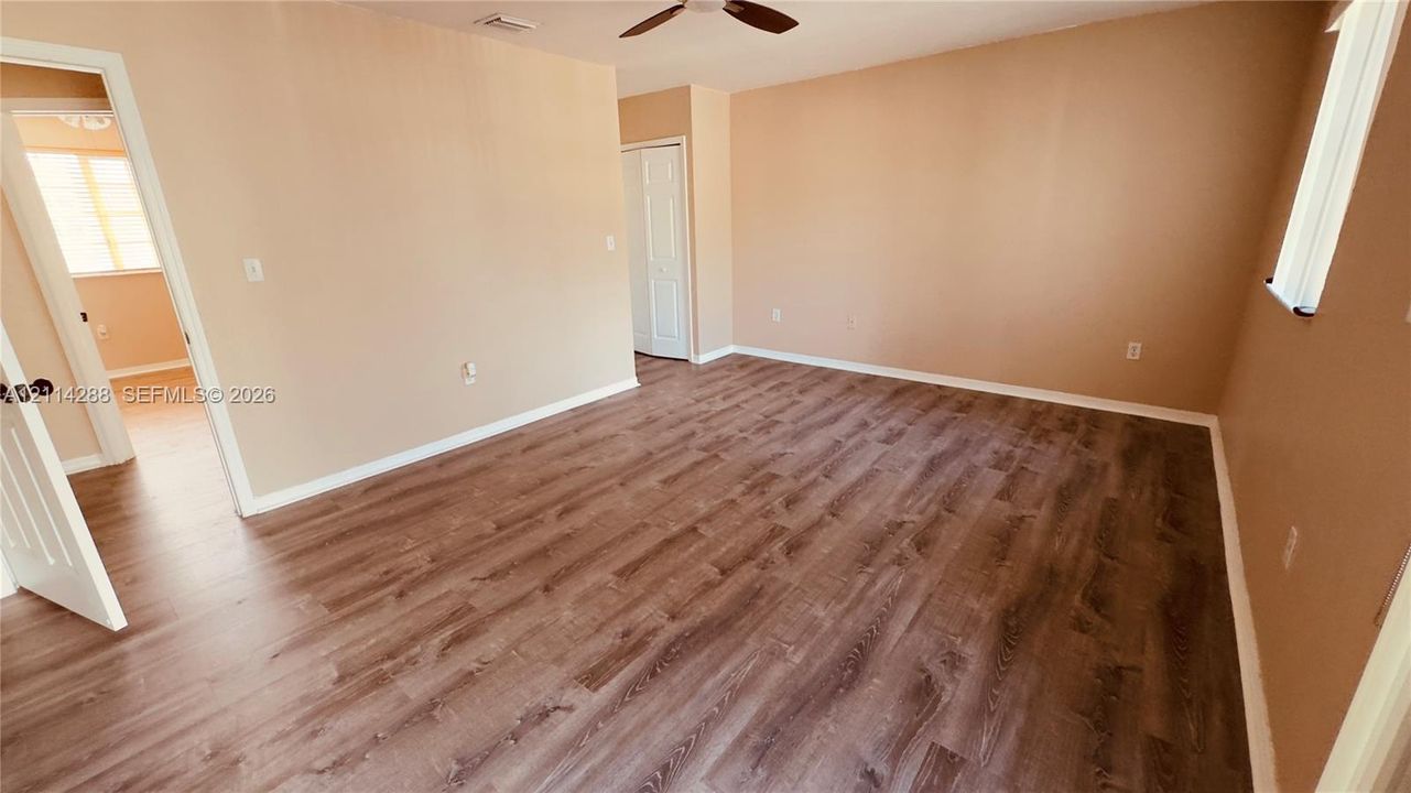 Interior room featuring wood-finish flooring, neutral wall paint, a ceiling fan, and a bi-fold closet door