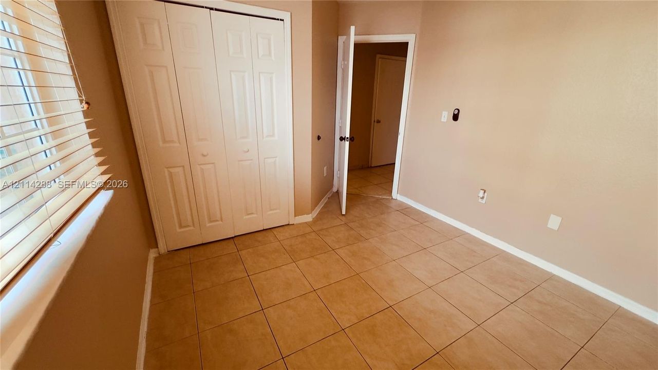 Room featuring tile flooring, bi-fold closet doors, and neutral wall paint
