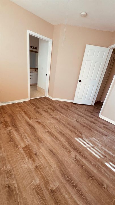 Interior space featuring wood-finish flooring, six-panel interior doors, and neutral wall paint
