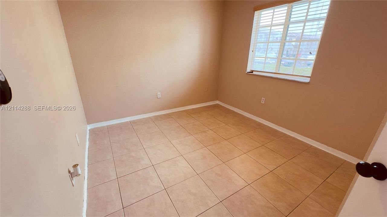 Neutral-toned interior space featuring light tile flooring and a multi-pane window