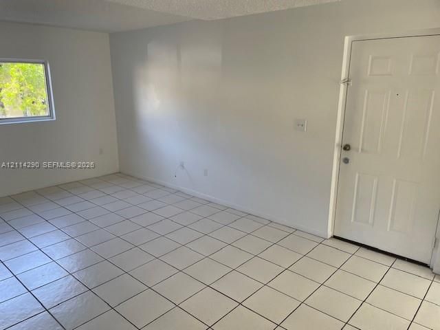 Neutral interior space featuring white walls, square ceramic tile flooring, and a six-panel exterior door