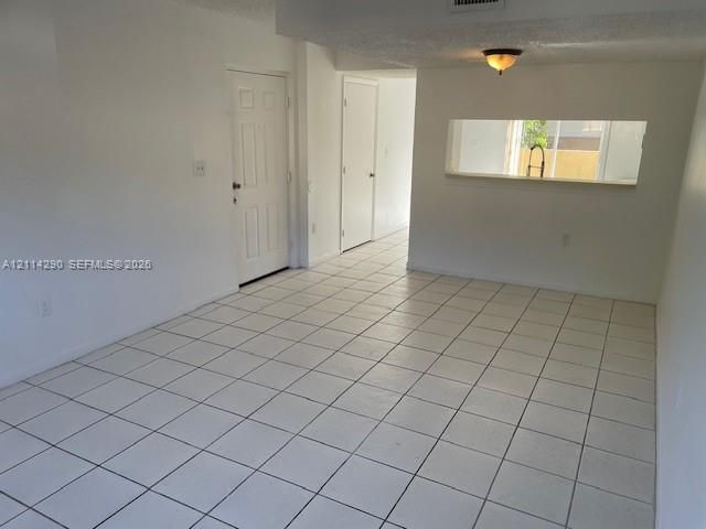 Ceramic tile flooring, pass-through opening to additional space, flush-mount lighting, and multi-panel interior doors