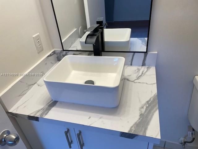 Vanity featuring a white-veined stone countertop, rectangular vessel sink, matte black faucet, and frameless rectangular mirror