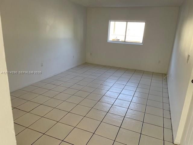 Interior room featuring neutral wall paint, white tile flooring, and a sliding glass window