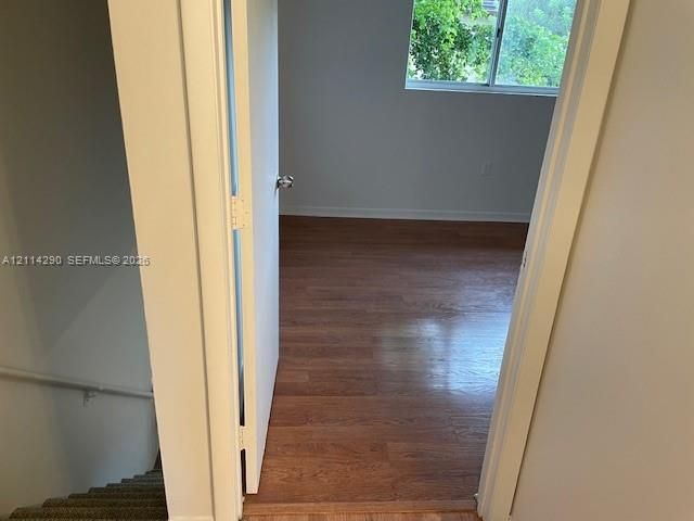 Room featuring wood-finish flooring, white walls, and a sliding window