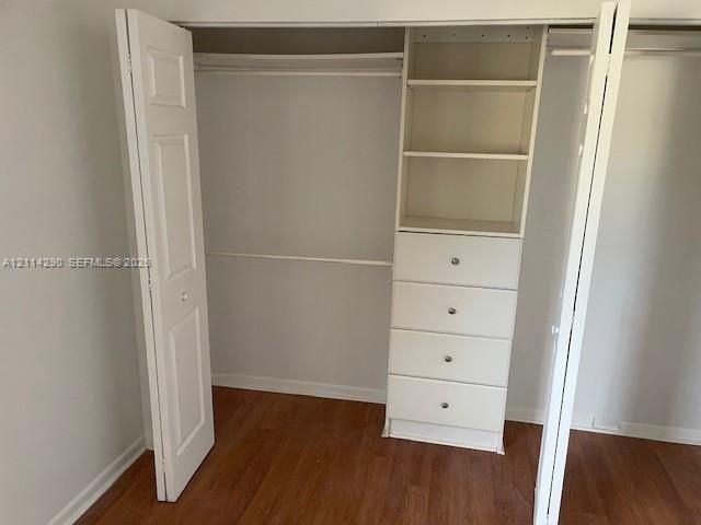 Closet featuring white bi-fold doors, built-in shelving, and four storage drawers with metallic hardware