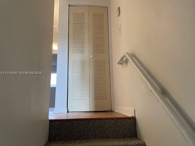 Bi-fold louvered closet doors, carpeted stairs, and a wall-mounted handrail