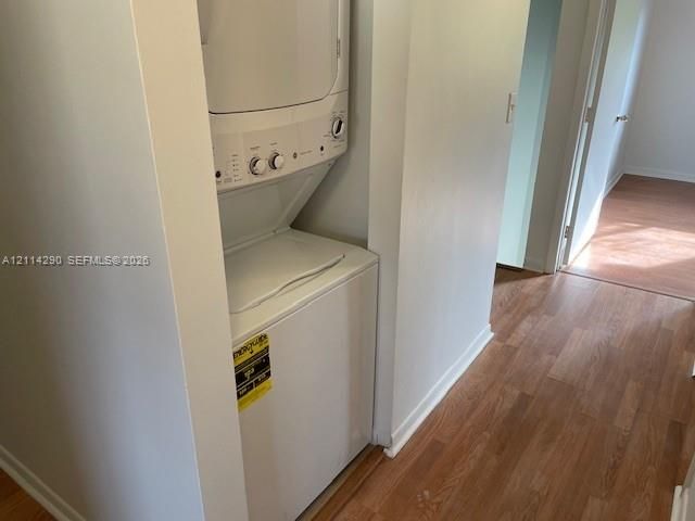 Stacked laundry unit enclosed in a dedicated alcove with wood-finish flooring