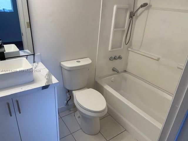 Bathroom featuring a white rectangular vessel sink, vanity with a light-toned patterned countertop, white cabinetry with silver-toned hardware, and a tub-shower combination with a handheld sprayer