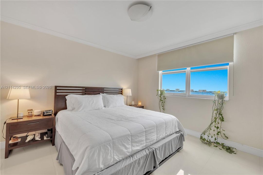 Neutral-toned interior featuring large-format tile flooring, crown molding, and a dual-pane window with water and horizon scenery
