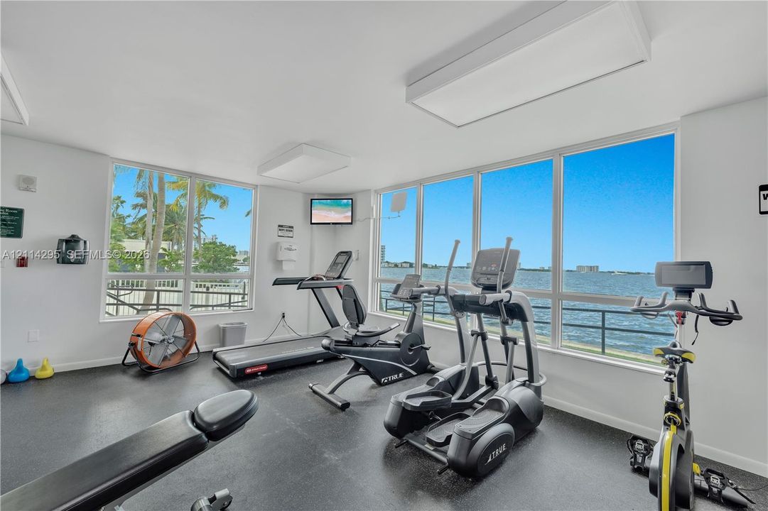 Fitness center featuring extensive floor-to-ceiling windows, water scenery, and resilient rubberized flooring