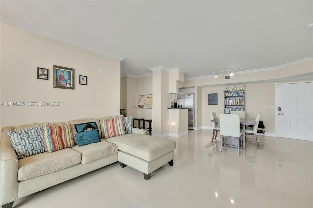 Open-concept interior featuring large-format tile flooring, crown molding, and a breakfast bar