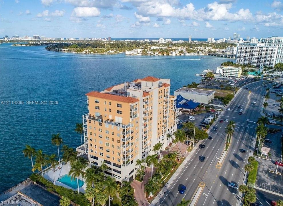 High-rise building with a terracotta roof, waterfront location, and ground-level pool with paver decking